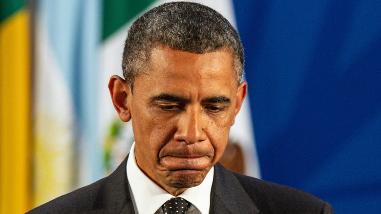 Barack Obama looking down and pursing his lips