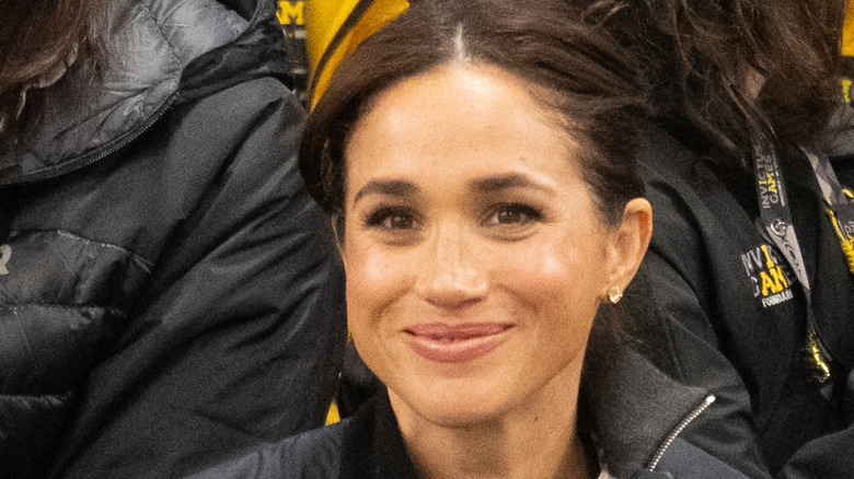 Meghan Markle smiling in a black jacket
