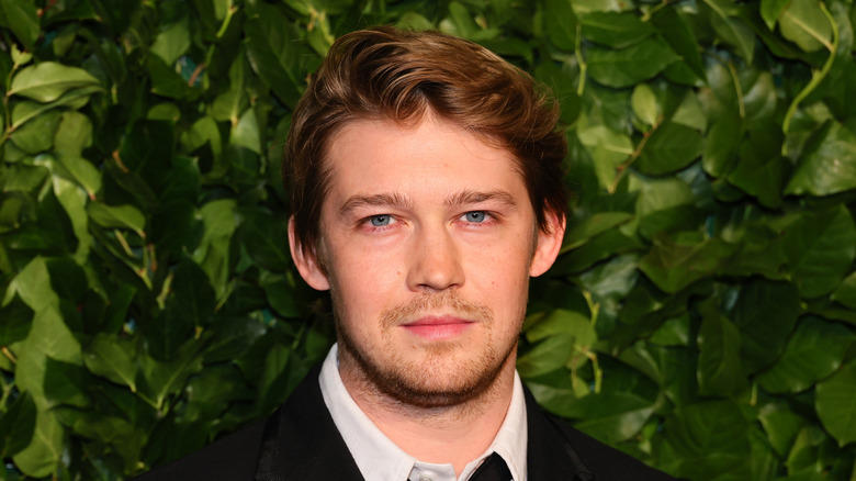 Joe Alwyn posing green background