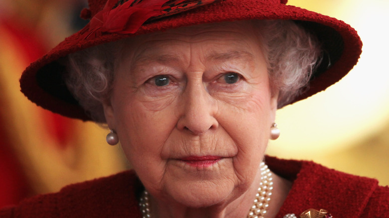 Queen Elizabeth looking stern in a hat and pearls