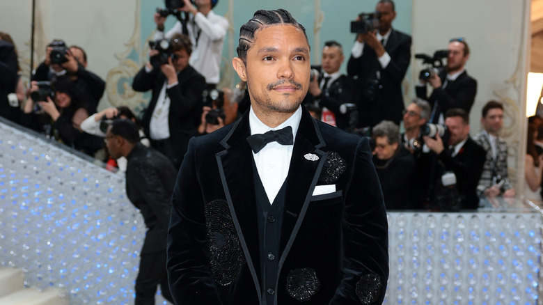 Trevor Noah smiling at red carpet event with cornrows