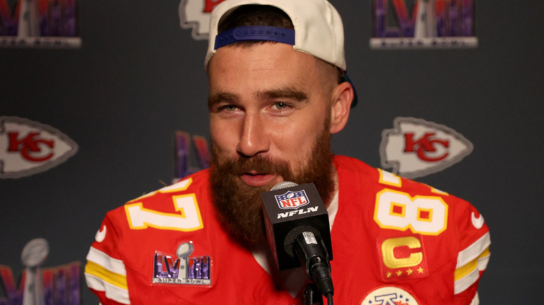 Travis Kelce smiling in close-up with microphone