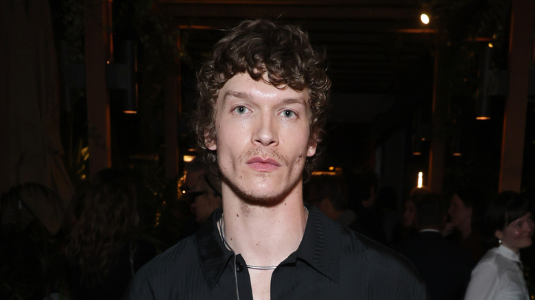 Connor Storrie wearing a black button down shirt and silver chain necklace