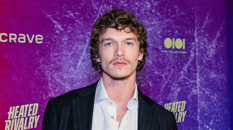 Connor Storrie wearing a black striped blazer and open white collared shirt