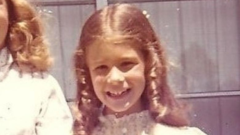 A young Melinda Gates, with curly hair, flashes a toothy smile.