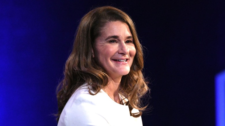Melinda Gates, with her curly hair, displays a broad smile.