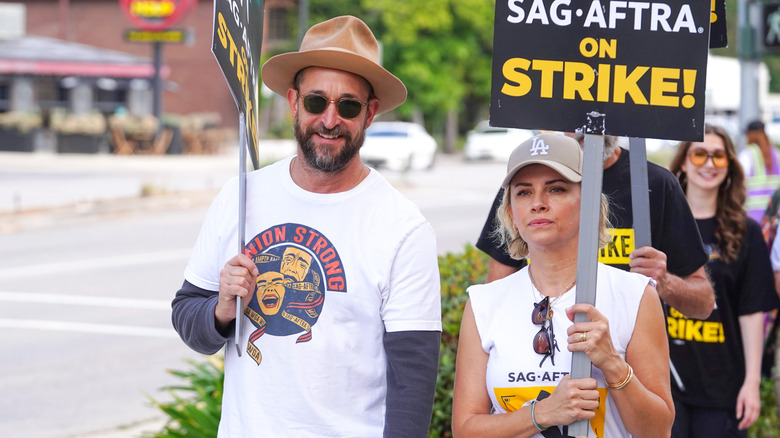 Noah Wyle and wife Sara Wyle picket during the SAG-AFTRA strike holding signs