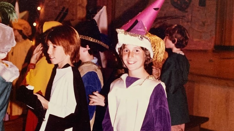 A young Noah Wyle wearing a pink wizard hat, purple shirt, and white apron backstage