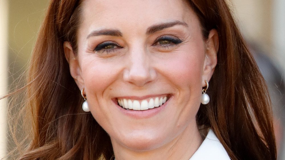 Kate Middleton smiling while wearing pearl earrings