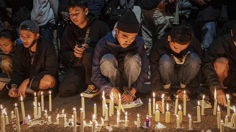 Arema football club supporters light candles as they pray for the victims on October 02, 2022