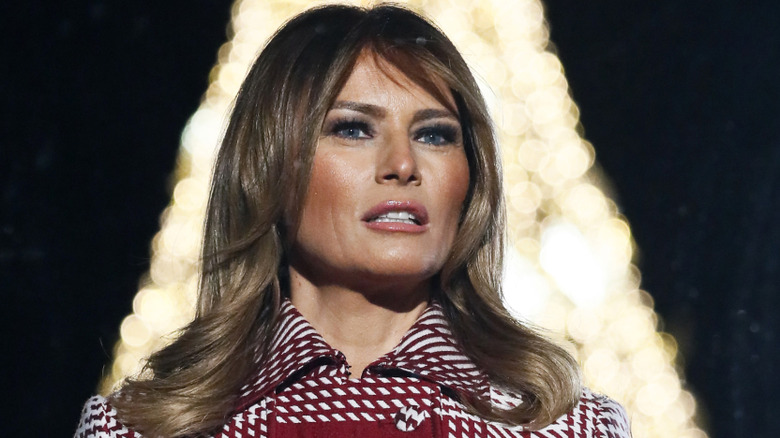 Melania Trump standing in front of a Christmas tree
