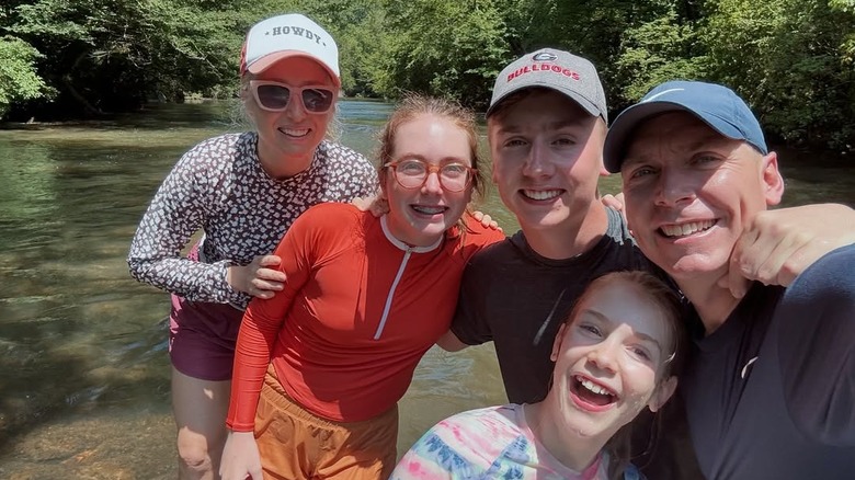Clint Harp poses with wife and three children by a river