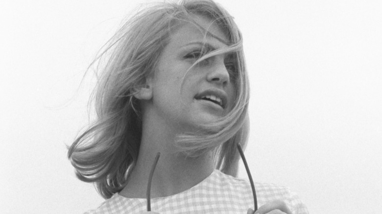Young Goldie Hawn poses holding sunglasses