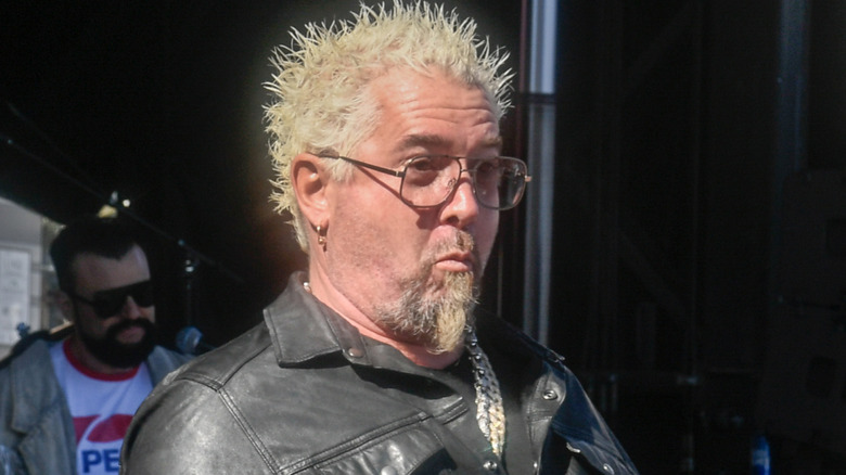 Guy Fieri posing for cameras outdoors while wearing leather