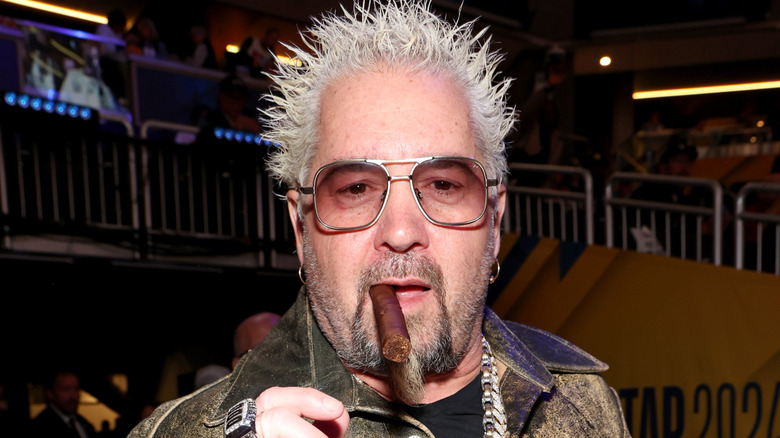 Guy Fieri posing for cameras with a cigar in his mouth