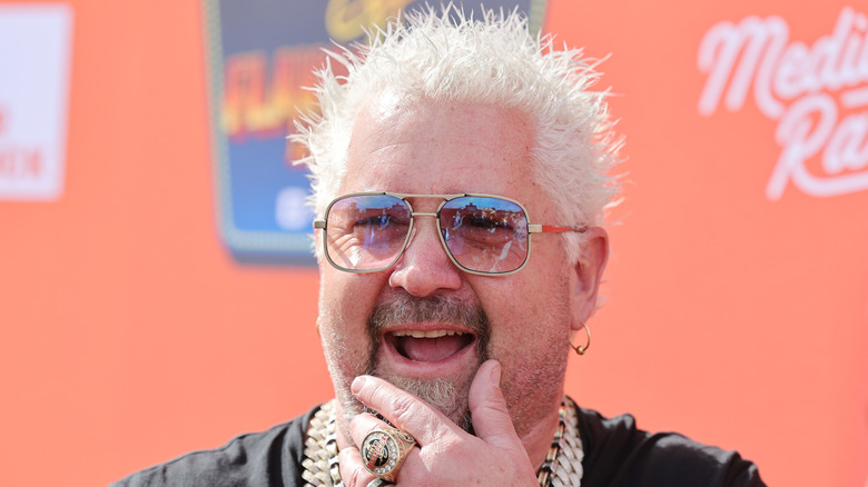 Guy Fieri posing for cameras wearing jewelry