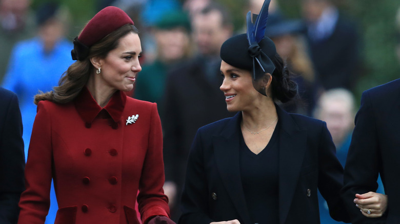 Kate Middleton and Meghan Markle looking at one another outside