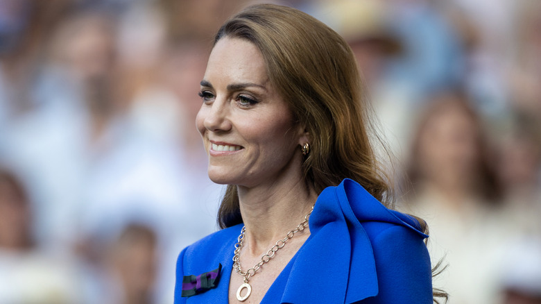 Kate Middleton smiling at Wimbledon while wearing a blue dress