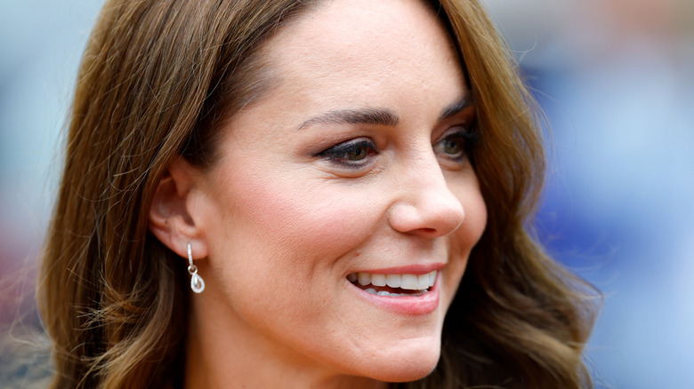 Kate Middleton smiling outdoors with a blurred background