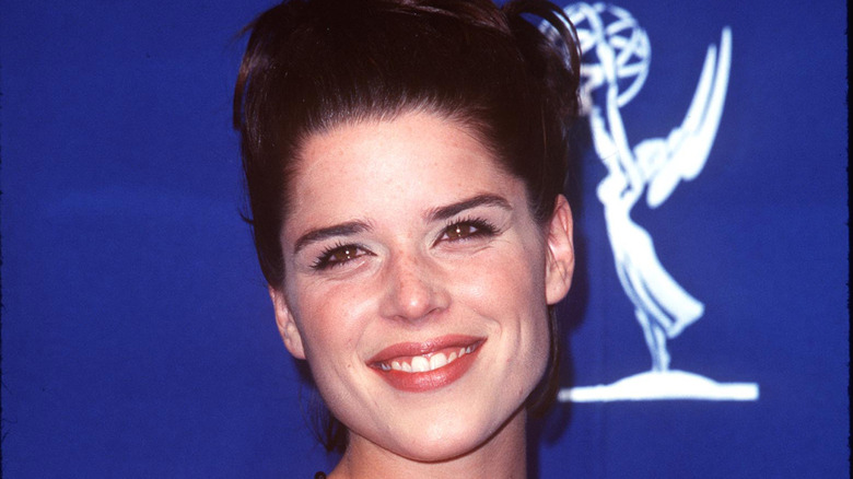 Neve Campbell smiling against a blue background