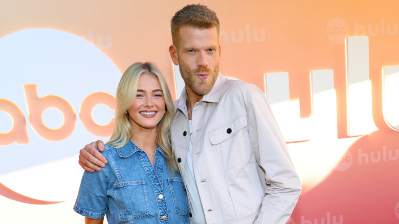 Scott Hoying puckering his lips and posing with his arm around a smiling Rylee Arnold