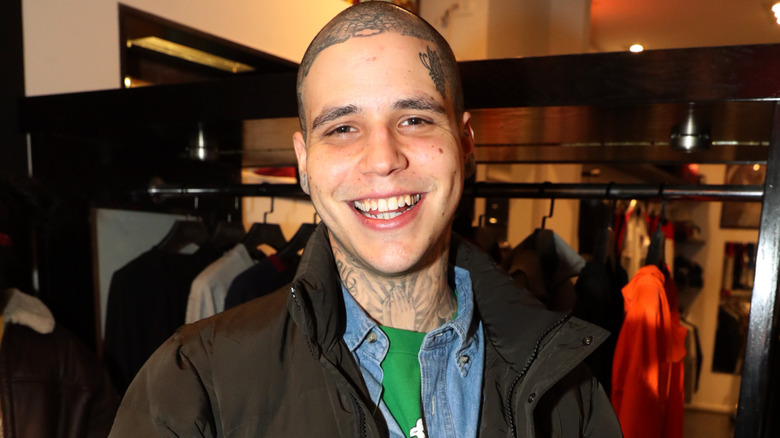 Richard Hilfiger smiling for cameras with a clothing rack behind him