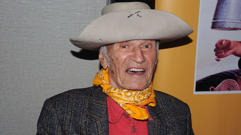 Larry Storch, wearing a cowboy hat and yellow scarf