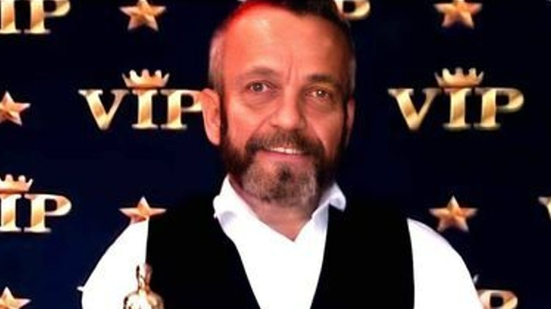 Paul Grant smiling and holding a golden award statue
