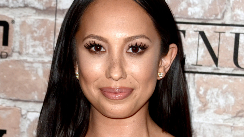 Closeup of Cheryl Burke posing in front of a brick background