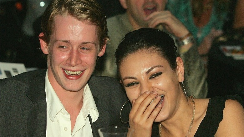 Macauley Culkin and Mila Kunis, both laughing