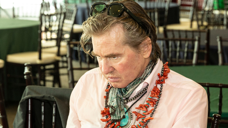 Val Kilmer with chairs and tables in the background