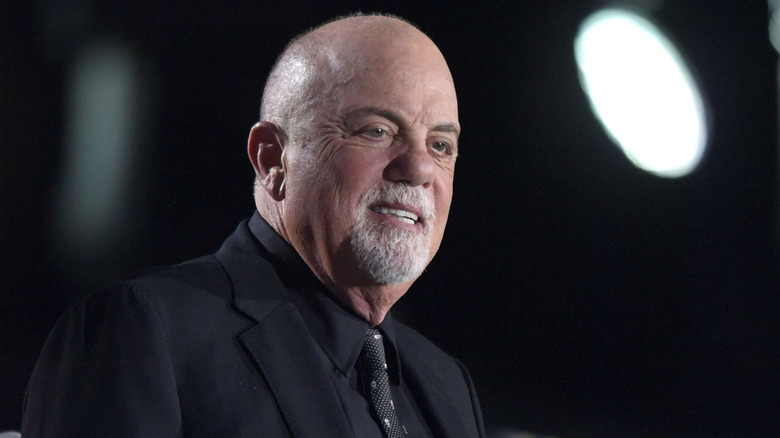 Billy Joel smiling underneath a light