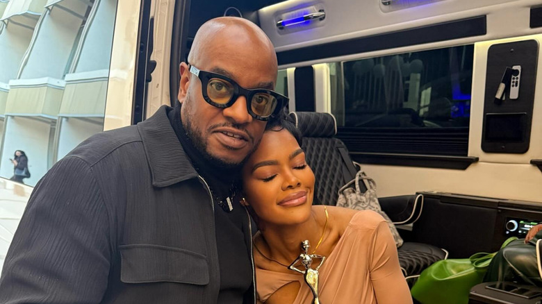 Teyana Taylor closes her eyes and poses with her head on her stepdad's shoulder while holding her Essence award.