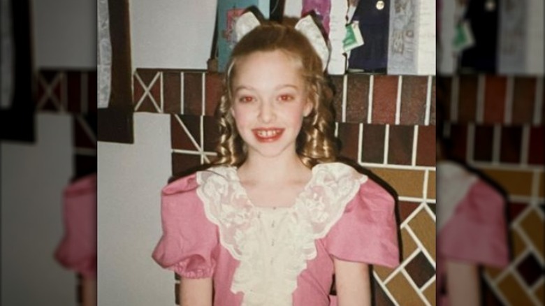 Young Amanda Seyfried smiling, in costume for "A Christmas Carol"
