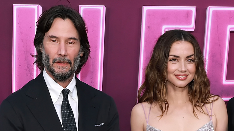 Keanu Reeves wearing a black tux and polka dot tie with Ana de Armas wearing a strappy sparkling gown