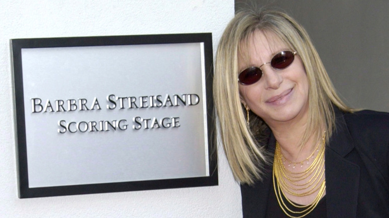 Barbra Streisand in sunglasses next to Barbra Streisand Scoring Stage sign