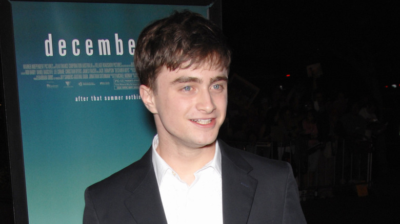 Daniel Radcliffe poses in dark jacket and white shirt.