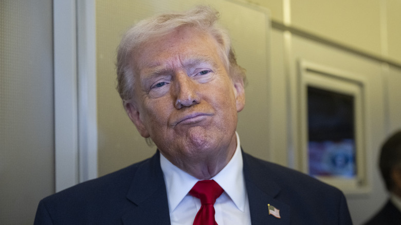 Donald Trump puckers his chin while speaking to reporters.