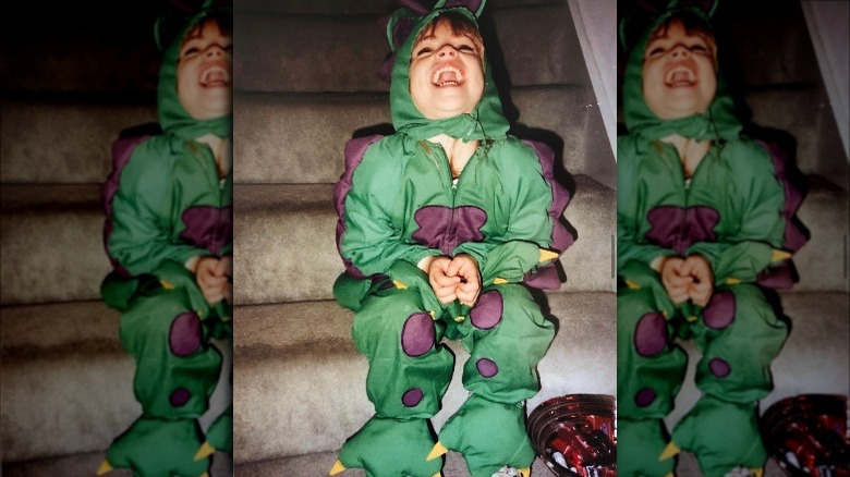 Young Emily Wickersham laughing in a dinosaur costume