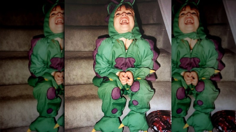 Young Emily Wickersham laughing in a dinosaur costume