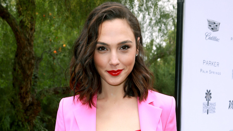 Gal Gadot posing in a pink blazer with a smirk