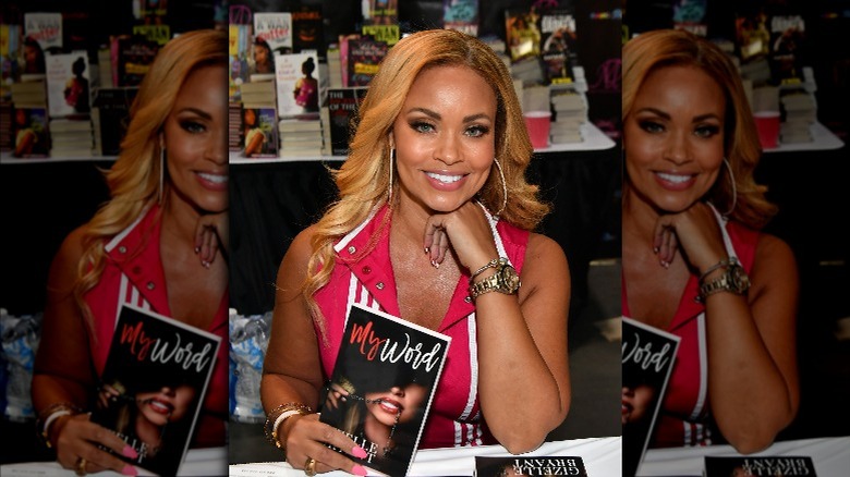 Gizelle Bryant, holding her book "My Word," smiling 