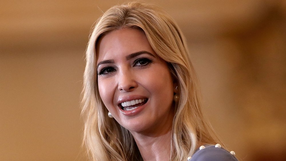 Ivanka Trump in a light purple blouse, smiling while looking to the side