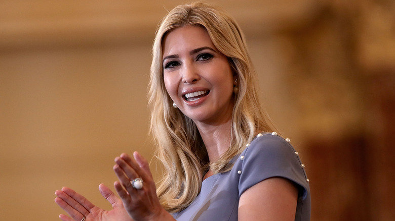 Ivanka Trump in a light purple blouse, smiling while looking to the side