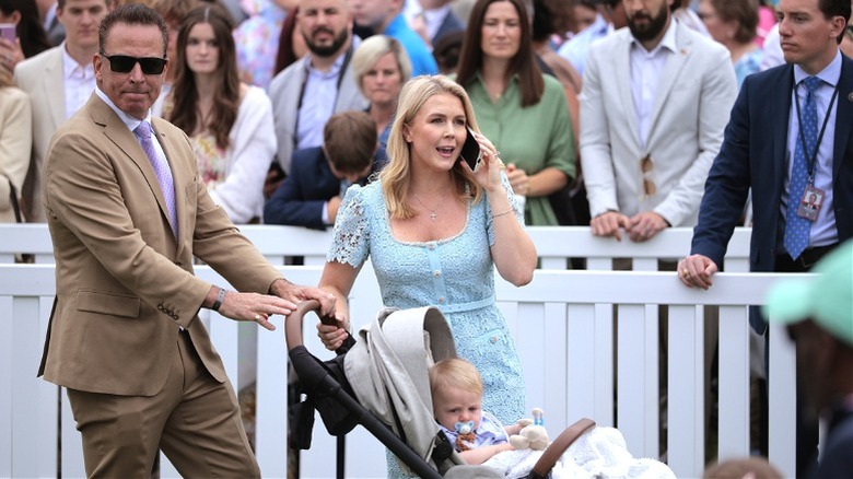 Karoline Leavitt and Nicholas Riccio hold their baby's stroller as she speaks on the phone.