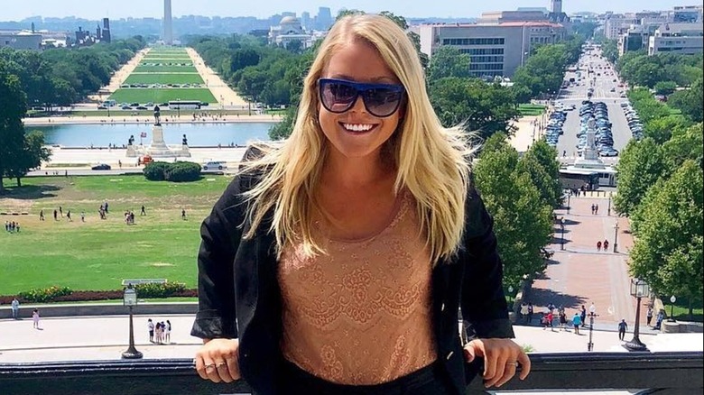 Karoline Leavitt smiles while leaning against a balcony in the US capitol building.