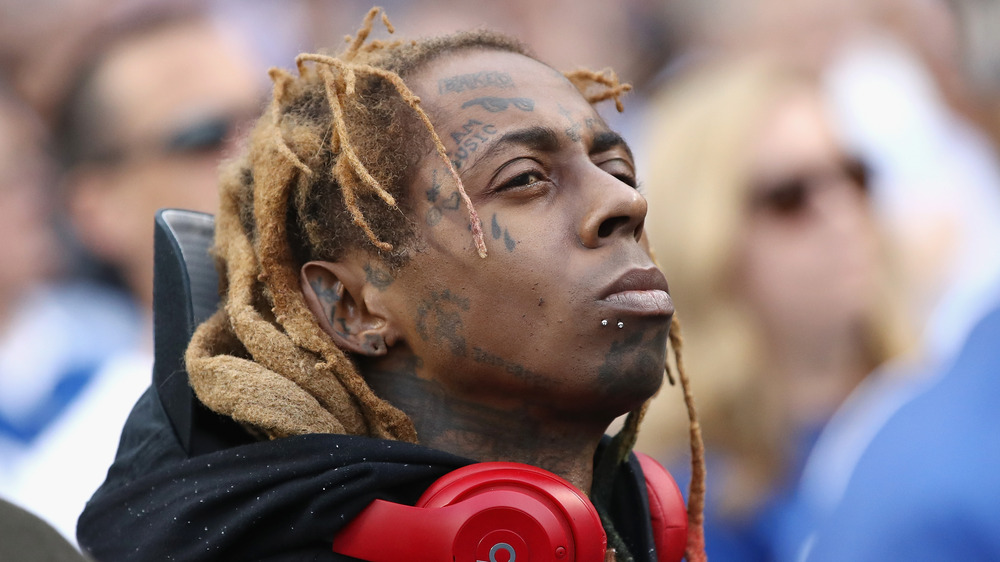 Lil Wayne looking on with red headphones around his neck