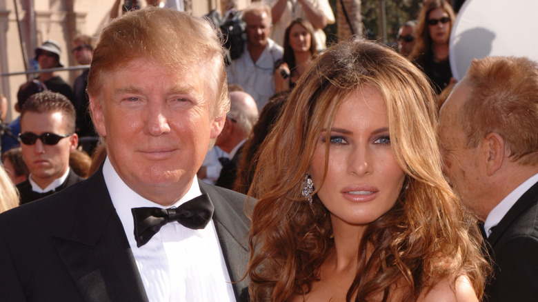 Melania Trump with wavy hair pouting next to Donald Trump