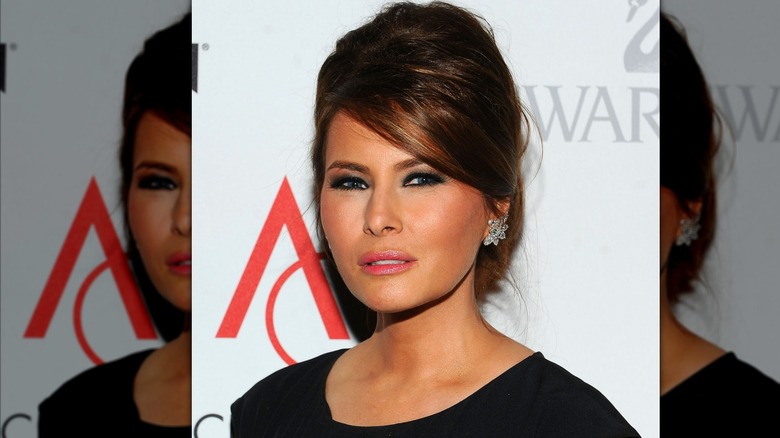 Melania Trump posing with diamond earrings and hair in updo