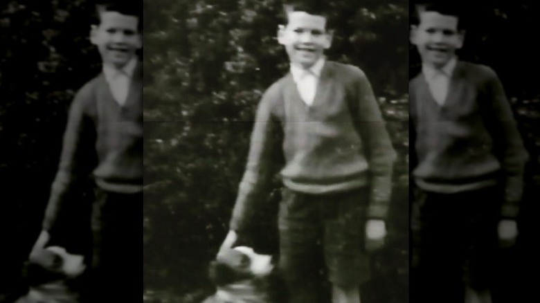 A young Pierce Brosnan petting his dog